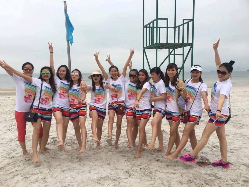 Đồng Phục Đi Biển Cho Chuyến Team Building Của Công Ty 1 Đoàn nhân viên mặc áo thun đồng màu chụp ảnh trên bãi cát buổi sớm