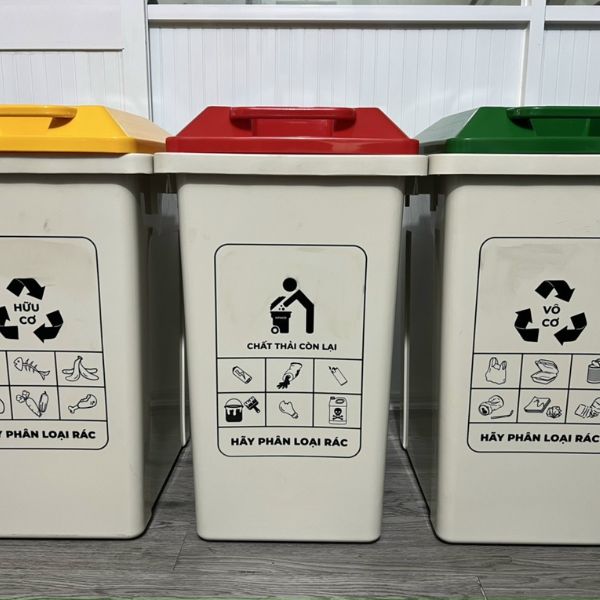 Thùng Rác Công Cộng Ngoài Trời - Vật Liệu Và Số Lượng 1 Thùng rác thân nhựa đặt ngoài trời trên vỉa hè, có nắp che và mặt thùng dán nhãn phân loại